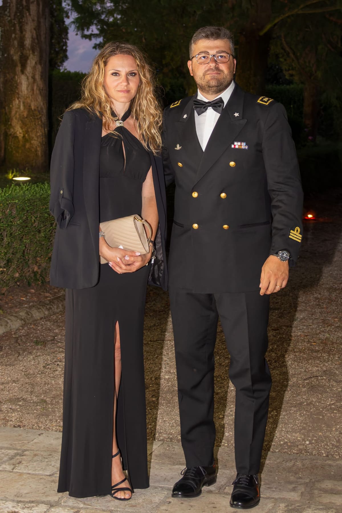 A member and her companion in the garden at dusk, evening dress and naval uniform