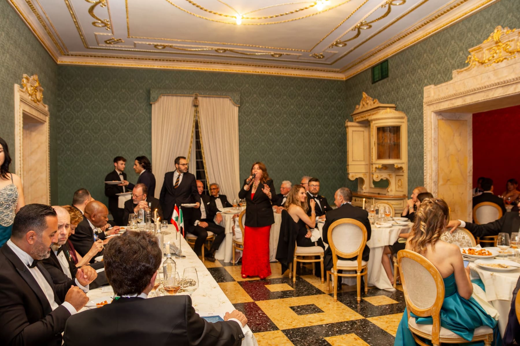 A long dinner in a green salon with a gilded ceiling